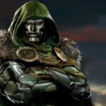 Doctor Doom, wearing a metallic mask and green hooded cloak with fur trim, stands against a dark sky.