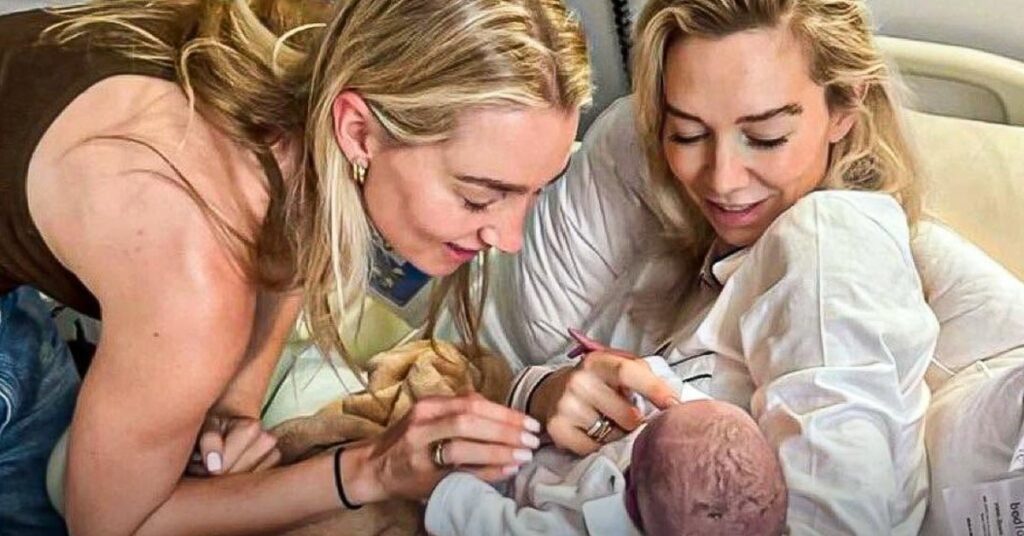 Vanessa Kirby smiling with loved one, joyfully holding her newborn baby in hospital bed.